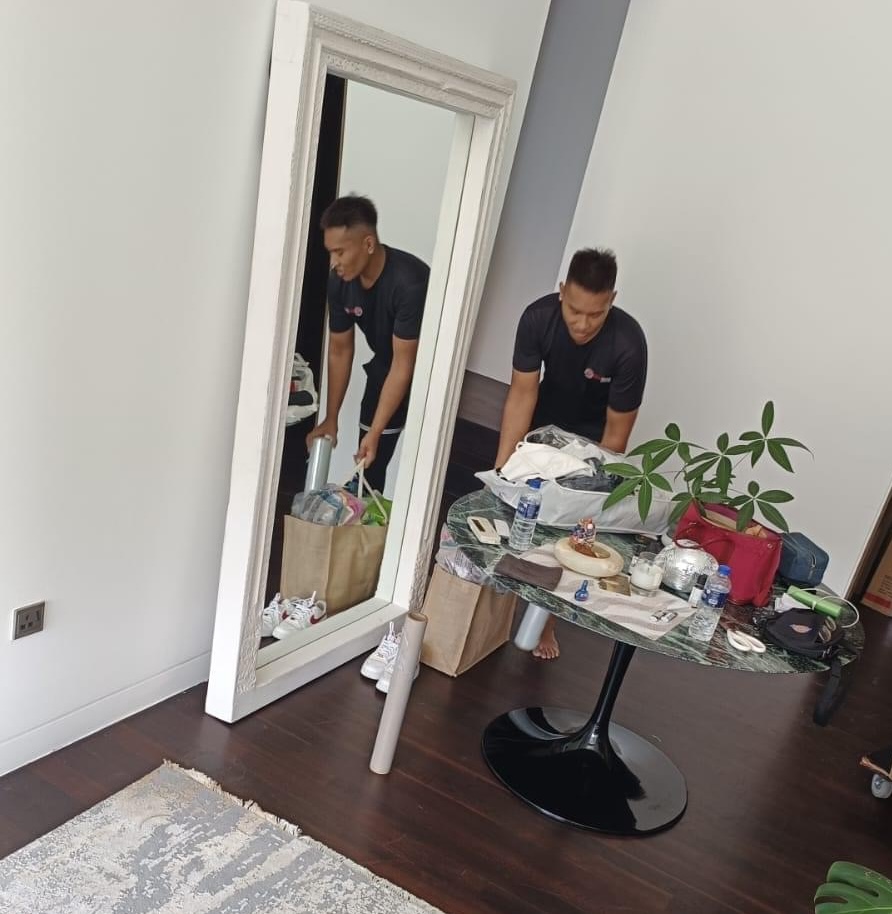 Movers organising furniture and packing items before Singapore-Malaysia cross-border move