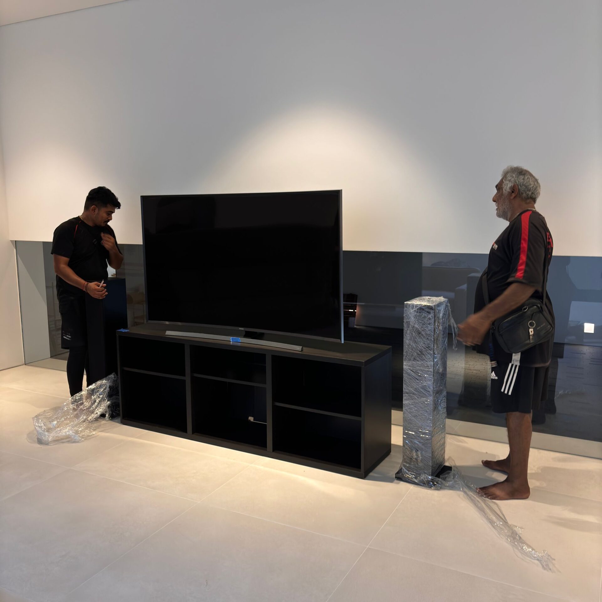 Professional movers handling a large flat-screen television during a residential move in Singapore.